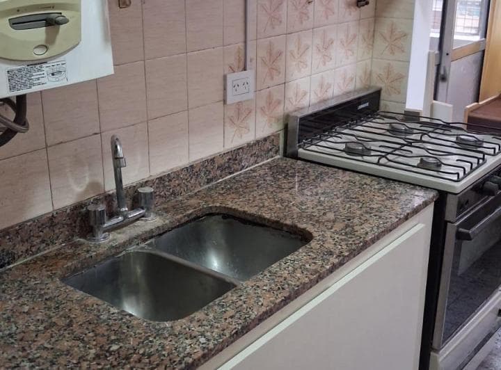 Cocina con bacha doble, anafe, mesada de granito y azulejos decorados.