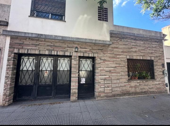 Fachada de la casa con ladrillo a la vista y rejas en ventanas.