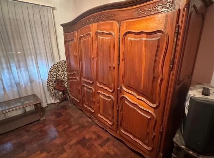 Dormitorio con gran placard de madera tallada y piso de madera.