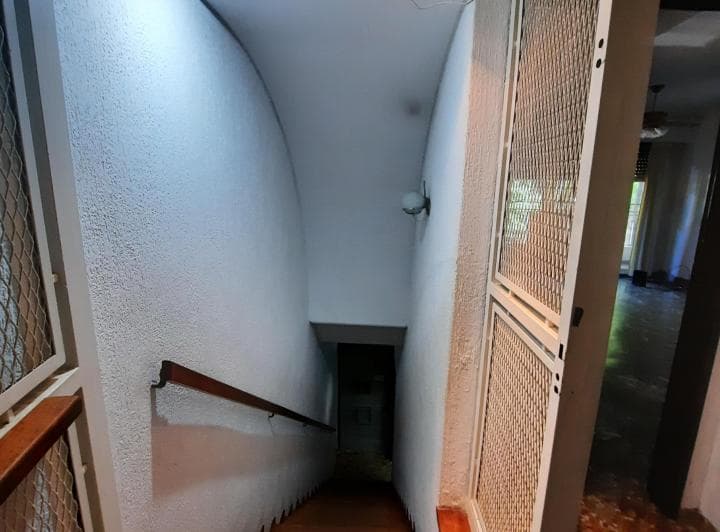 Pasillo con escalera caracol de madera y paredes blancas texturadas.