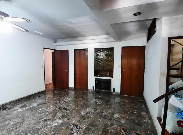 Living vacío con piso de mármol, varias puertas de madera y estufa.