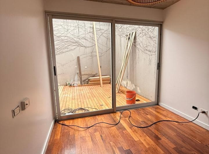 Cuarto vacío con puertas corredizas de vidrio que dan a un patio con enredadera.