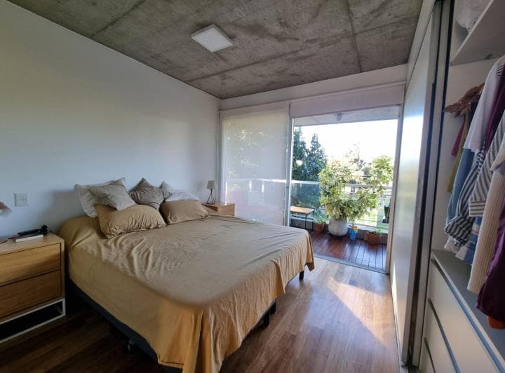 Dormitorio con cama doble, placard empotrado y salida a un balcón.