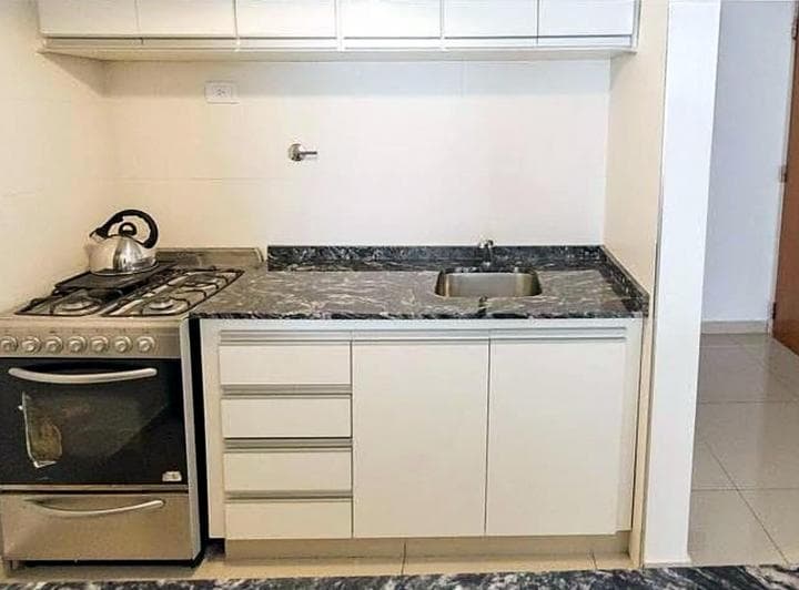 Cocina con anafe a gas, horno, bacha y mesada de granito oscuro.