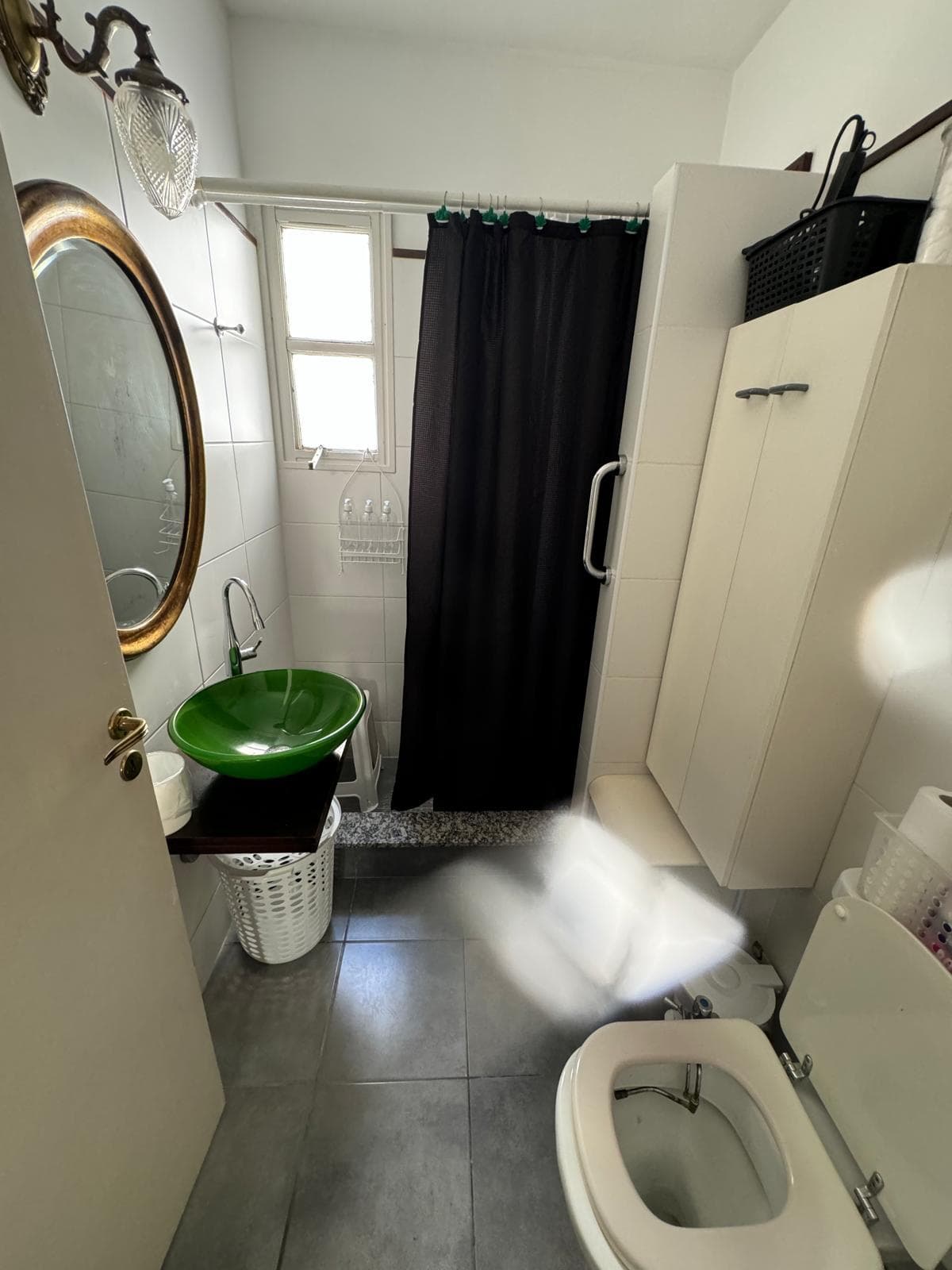 Baño completo con ducha, inodoro, bacha verde y espejo.