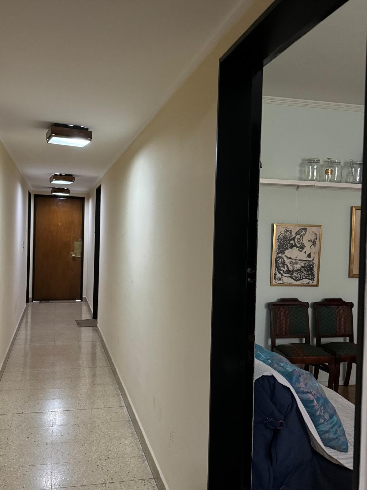 Pasillo de edificio con puertas de departamentos y piso de granito.