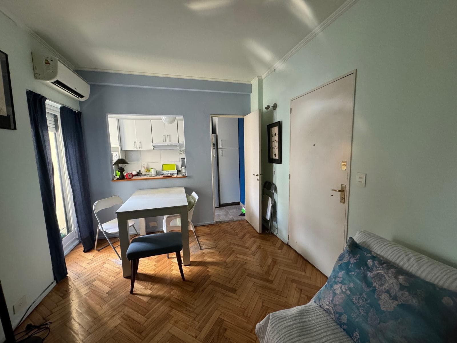 Living comedor con mesa, sillas, aire acondicionado y balcón.