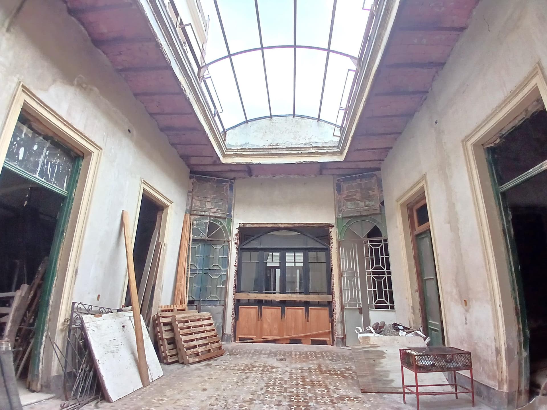 Patio interno con techo de vidrio, aberturas y materiales de construcción.