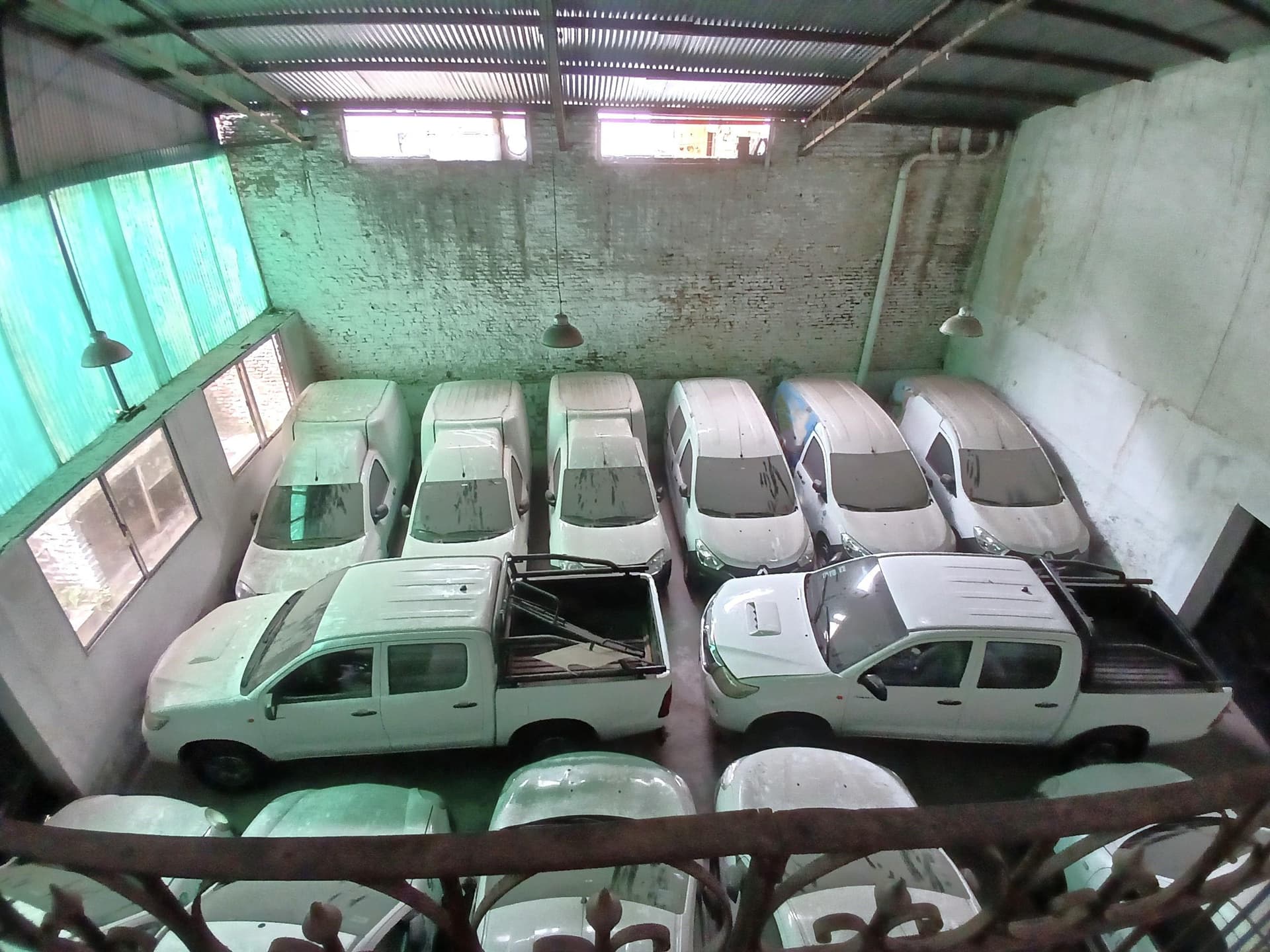 Garage con varios autos estacionados y un techo de chapa acanalada.