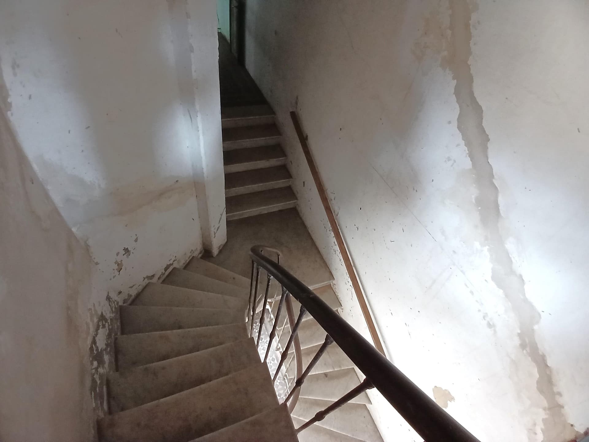 Escalera de mármol en espiral con baranda de hierro.