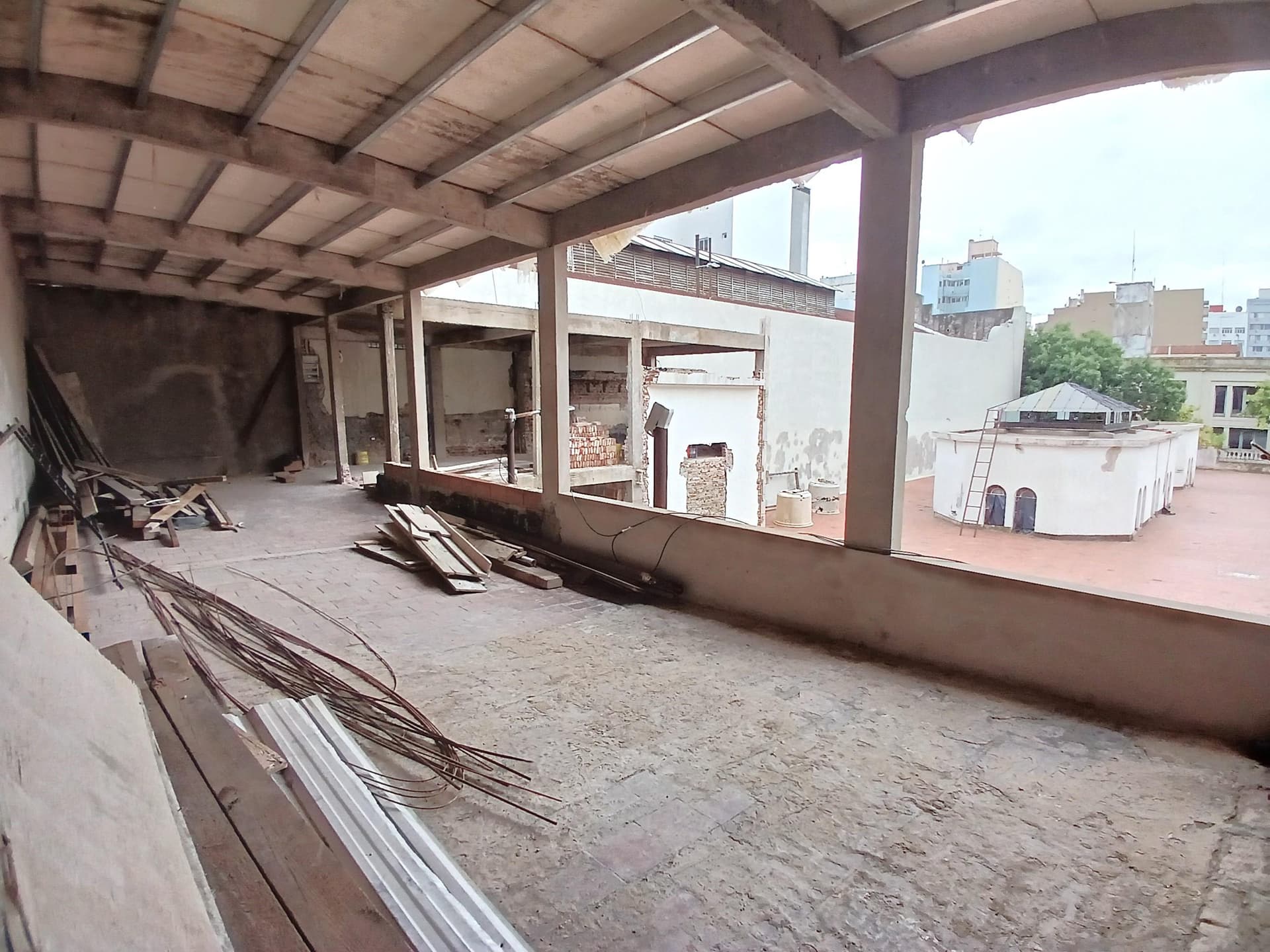 Espacio amplio en obra con columnas y vista a los techos de la ciudad.