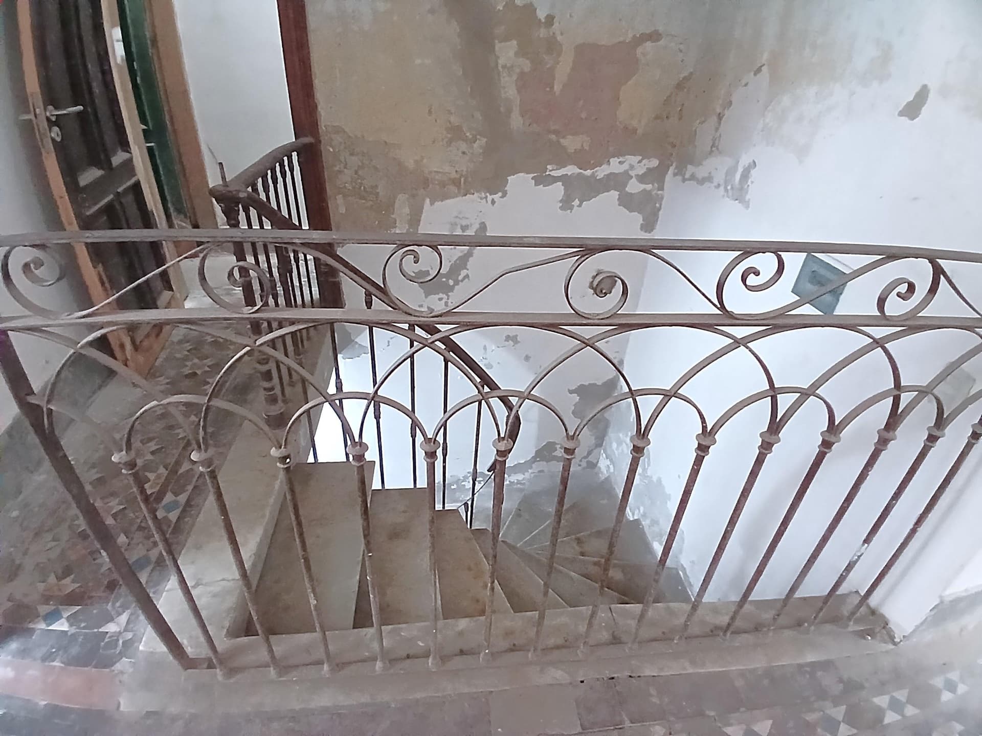 Escalera de mármol con baranda de hierro forjado.