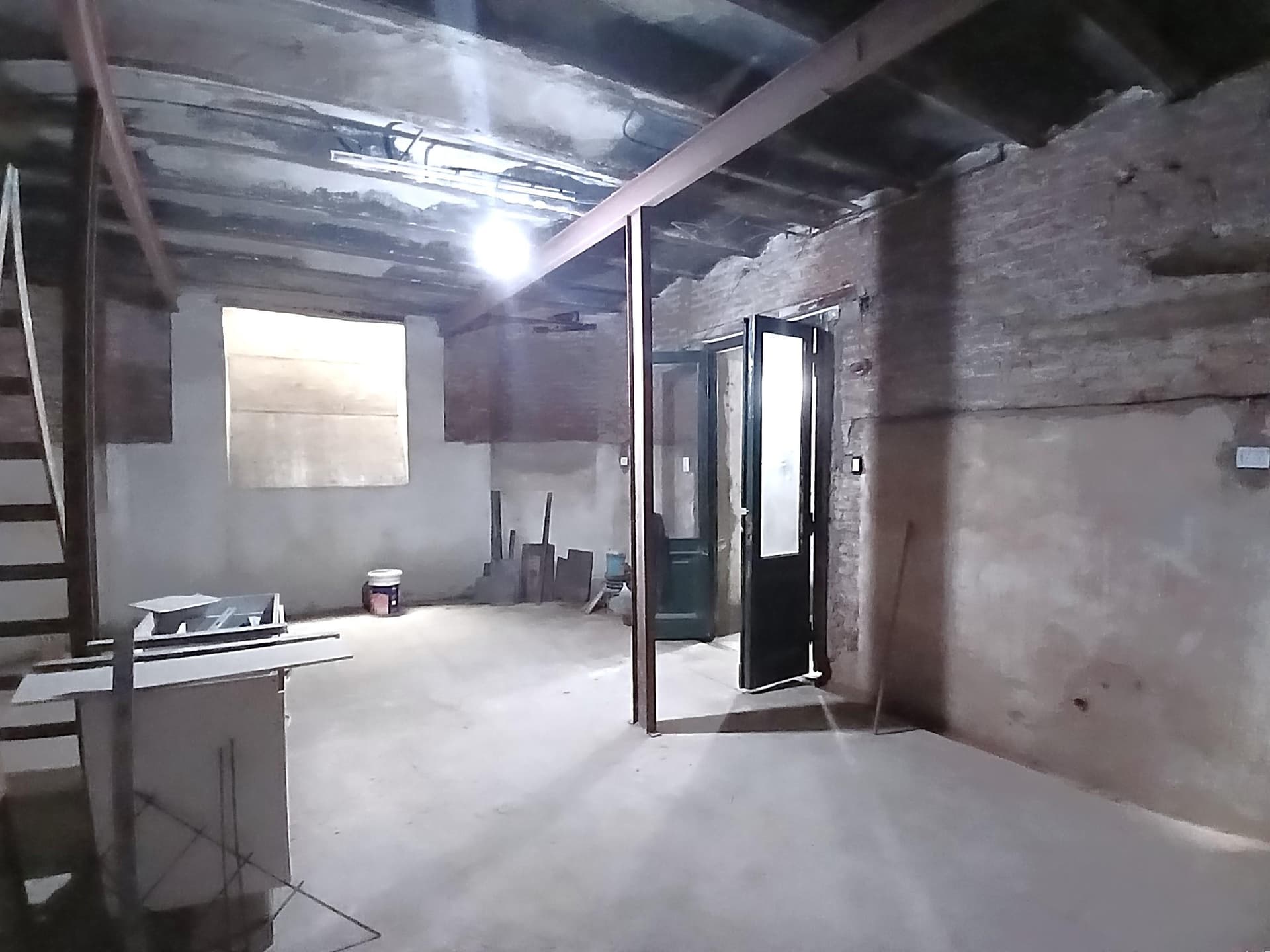Espacio amplio en obra con paredes de ladrillo y techo de chapa.