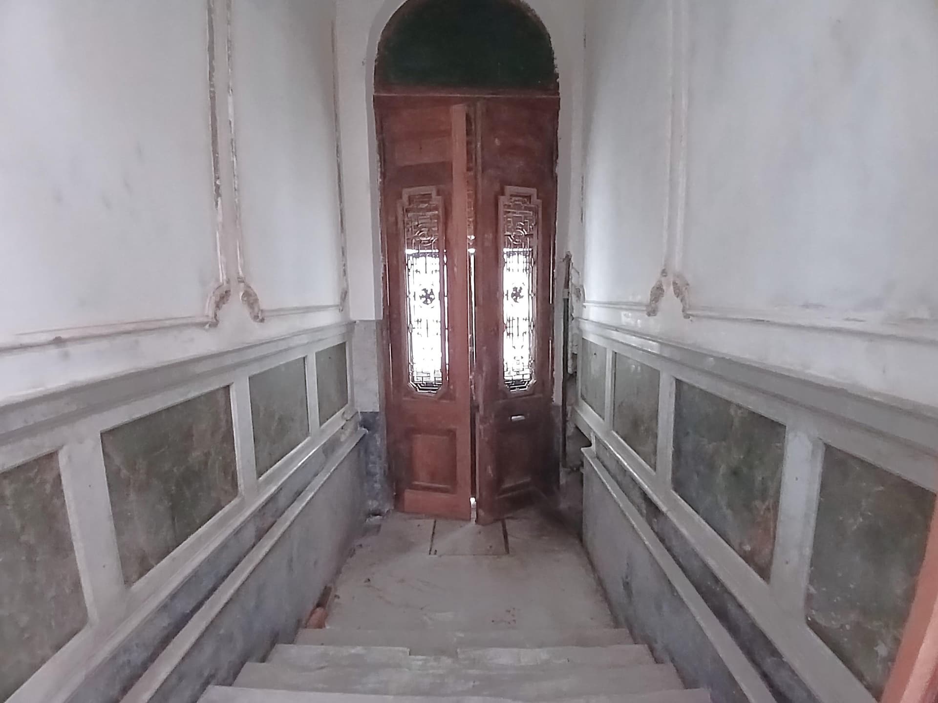 Escalera de entrada a la propiedad con puerta principal y paredes decoradas.
