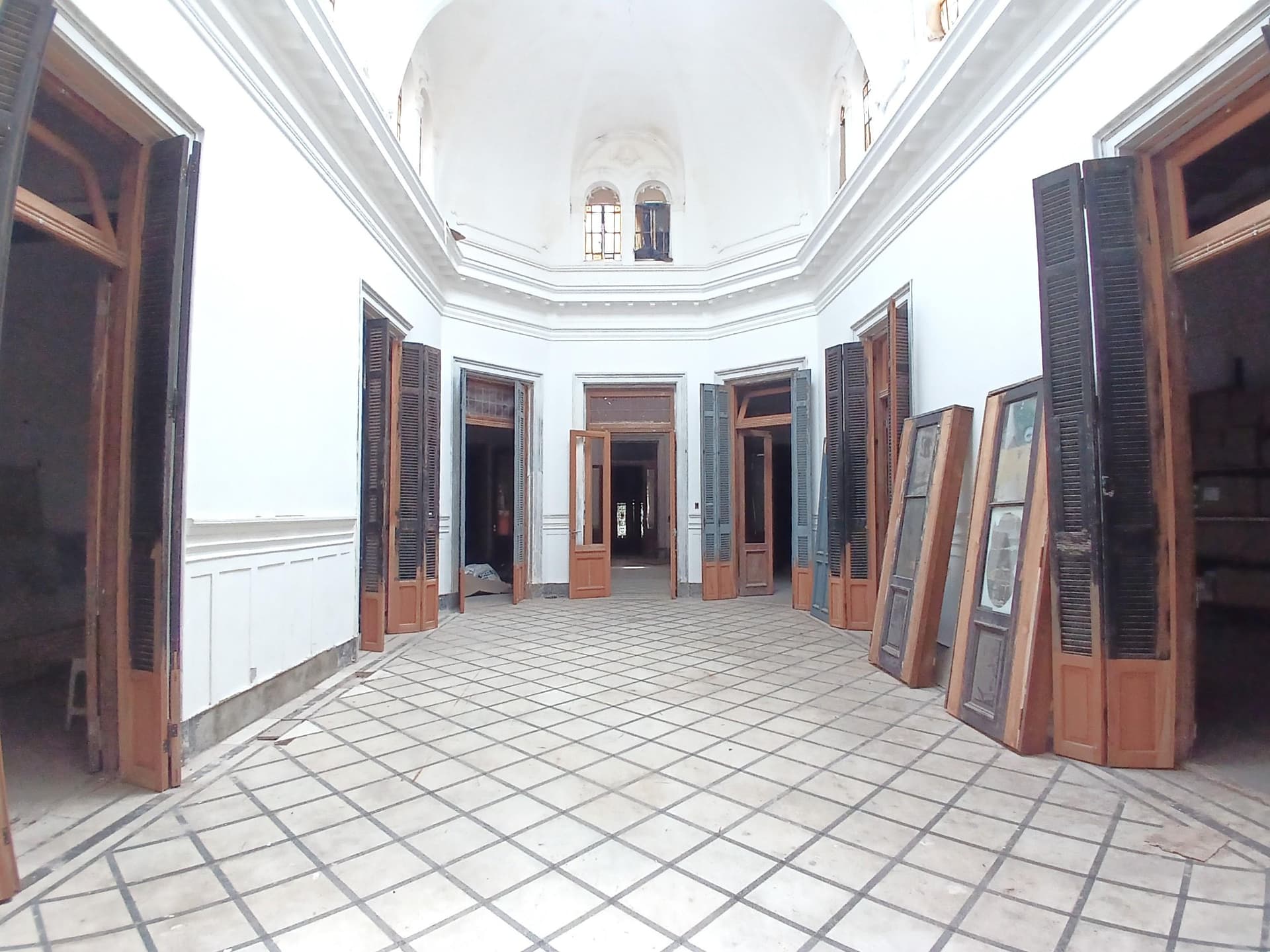 Pasillo de entrada con puertas y ventanas con celosías, y techo abovedado.