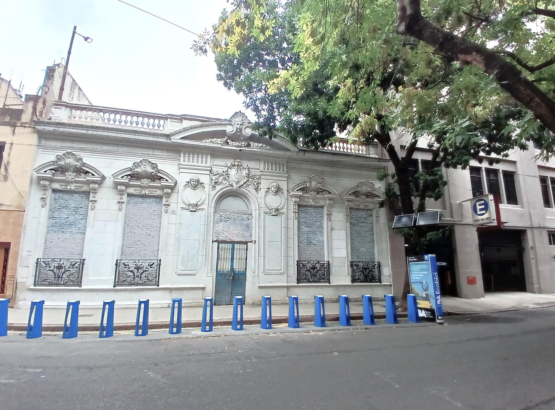 Fachada de edificio antiguo con detalles arquitectónicos y ventanas cerradas.