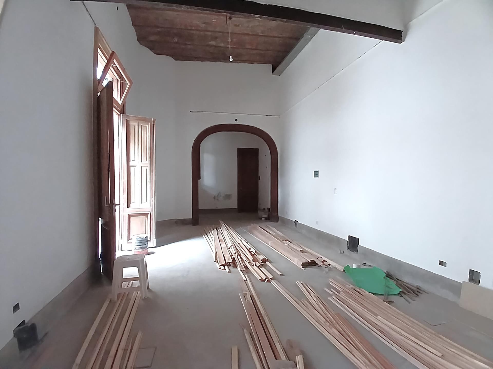 Dormitorio vacío con maderas en el piso y una puerta de acceso.