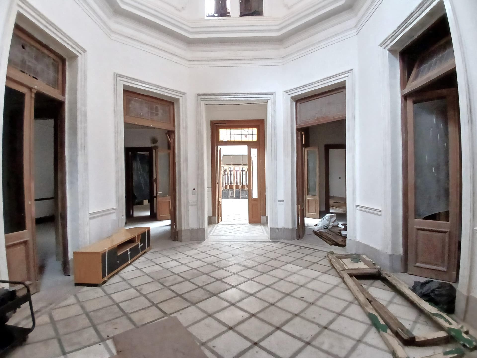 Hall de entrada octogonal con piso de baldosas y un mueble bajo.