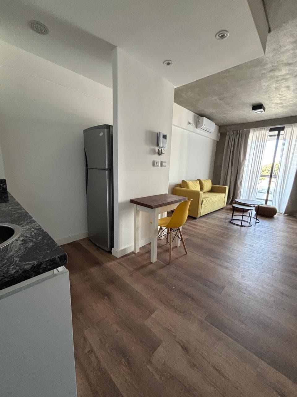 Vista del living desde la cocina, con heladera y sillón amarillo.