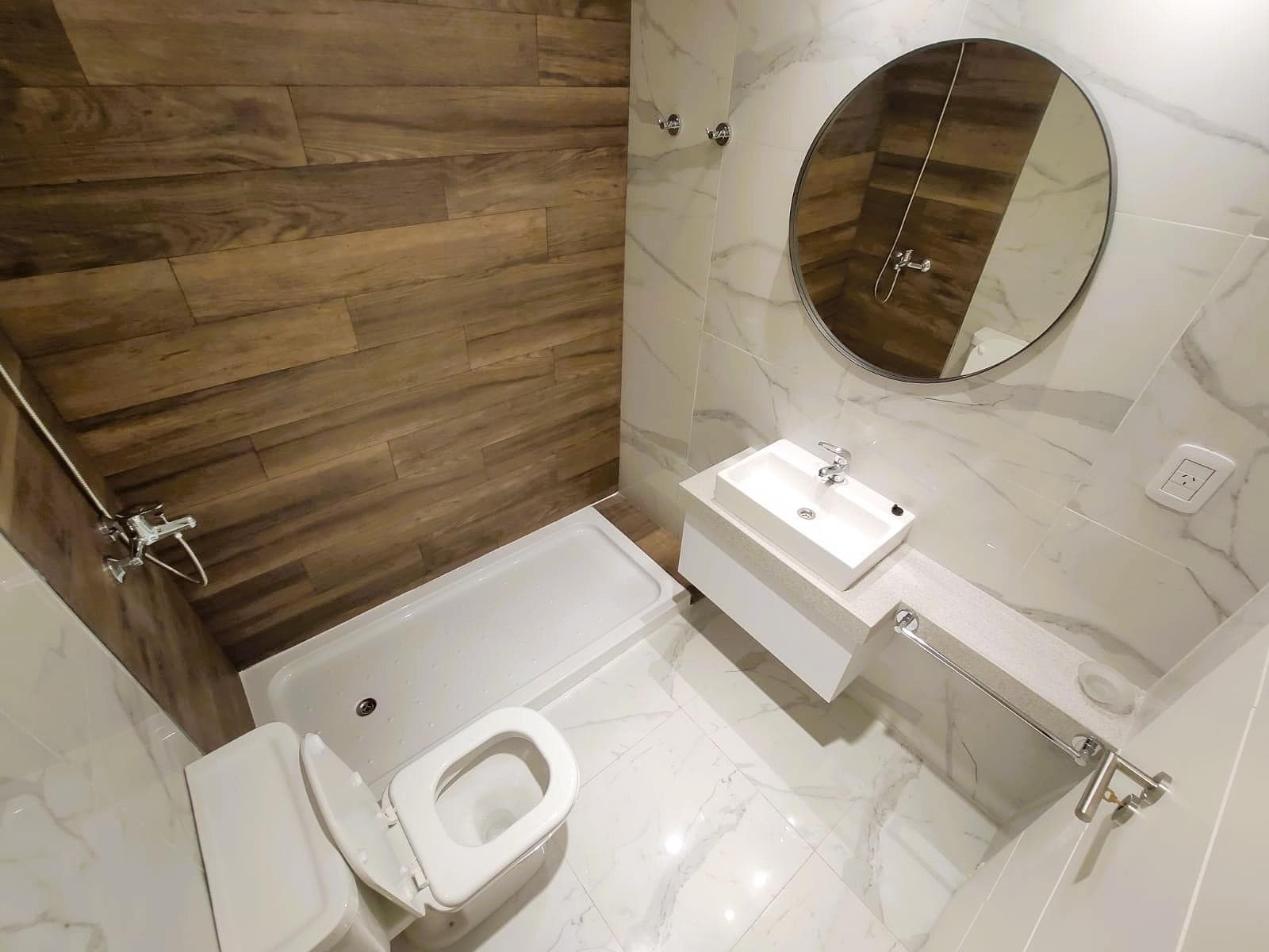Baño completo con inodoro, vanitory, espejo y ducha.