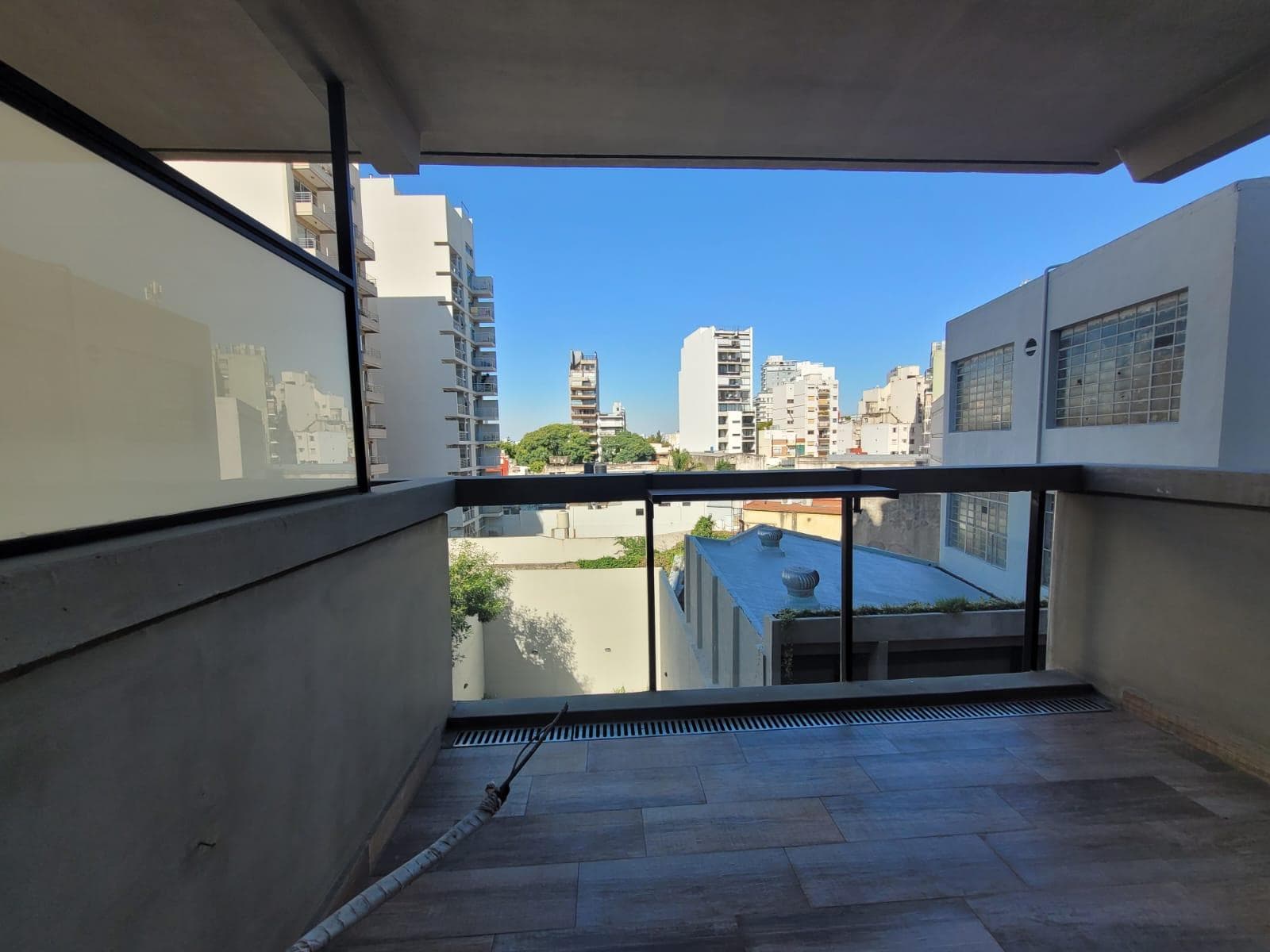 Balcón con baranda de vidrio y vista a los edificios de la ciudad.