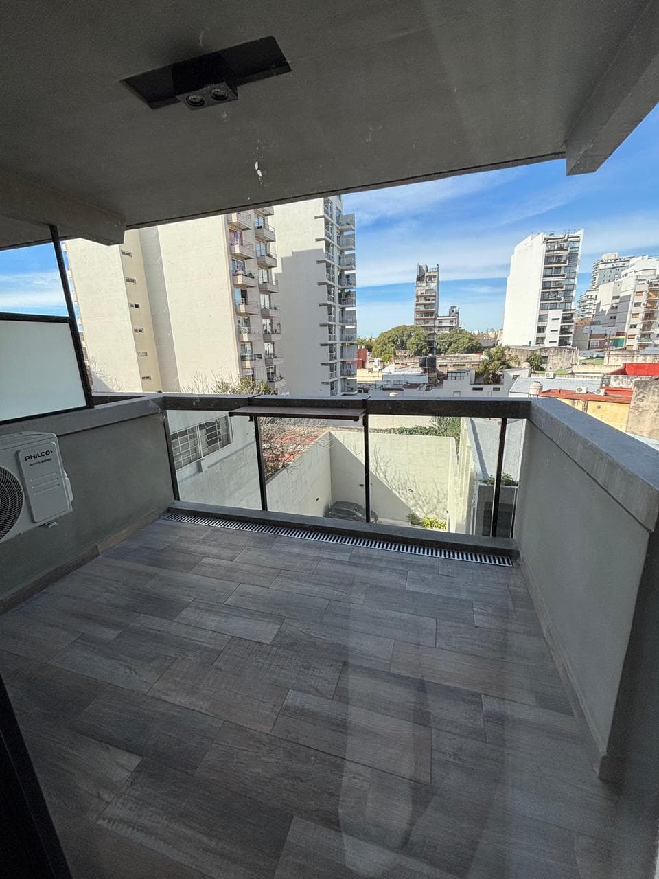Balcón con aire acondicionado exterior y vista a la ciudad.