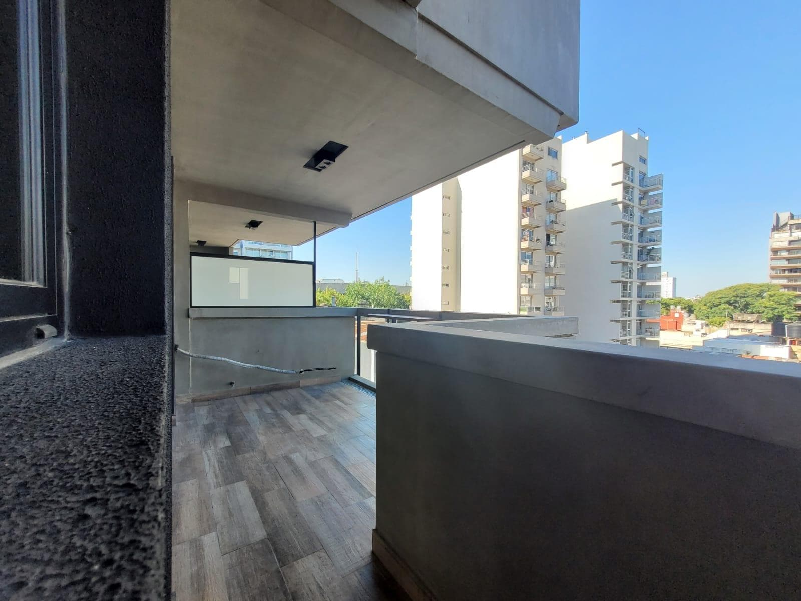 Balcón con baranda de vidrio y vista a edificios residenciales.