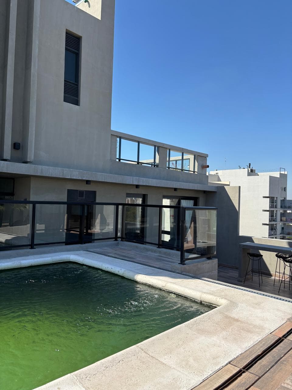 Pileta en la terraza con barandas de vidrio y vista panorámica.