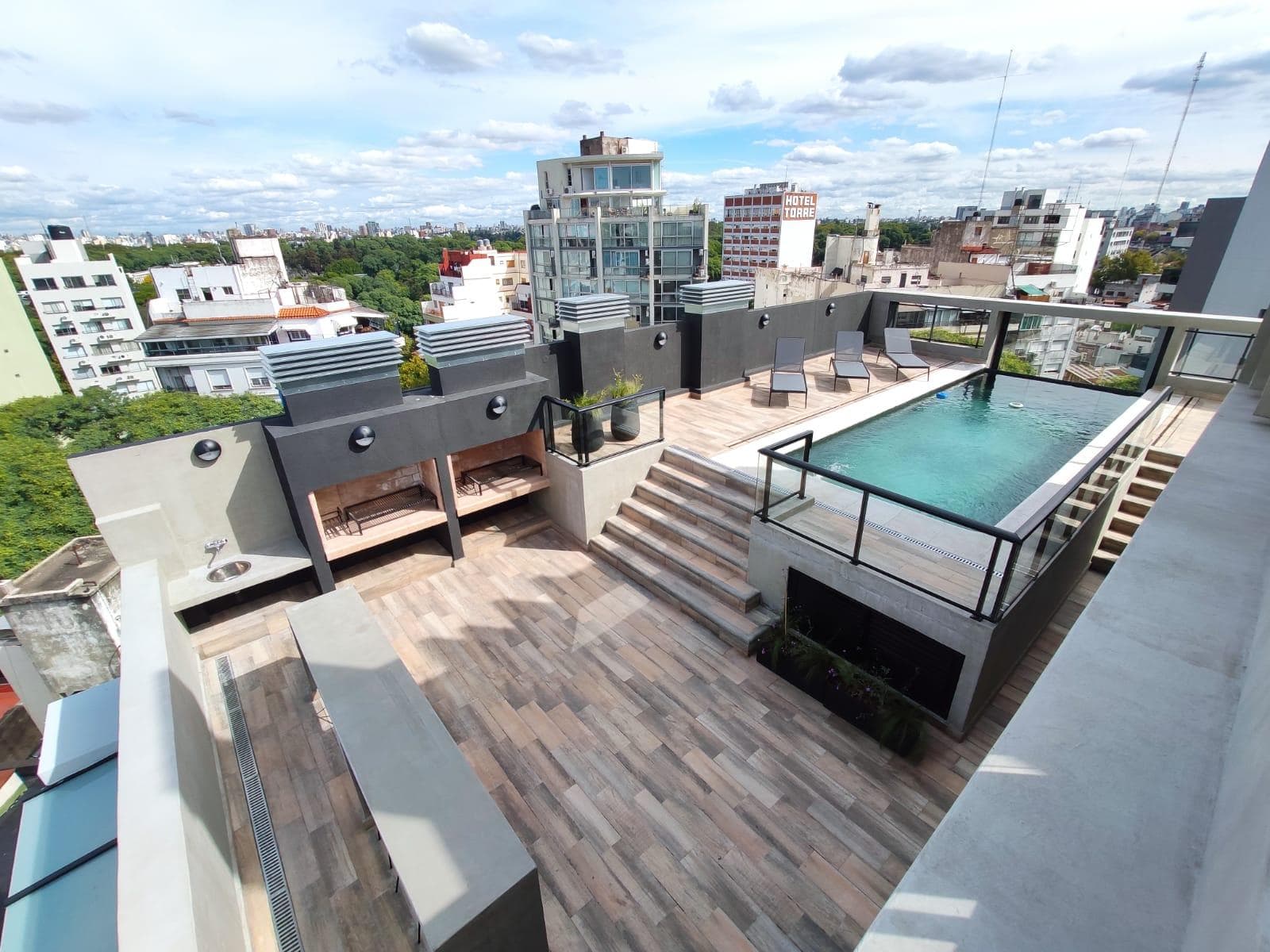Terraza del edificio con pileta, parrillas y vista a la ciudad.