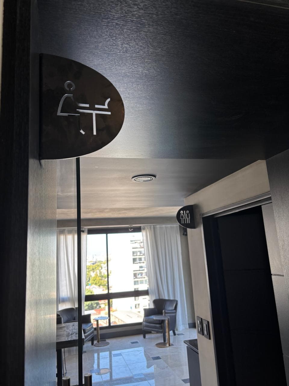 Señalización de baño en pasillo con vista a la calle.