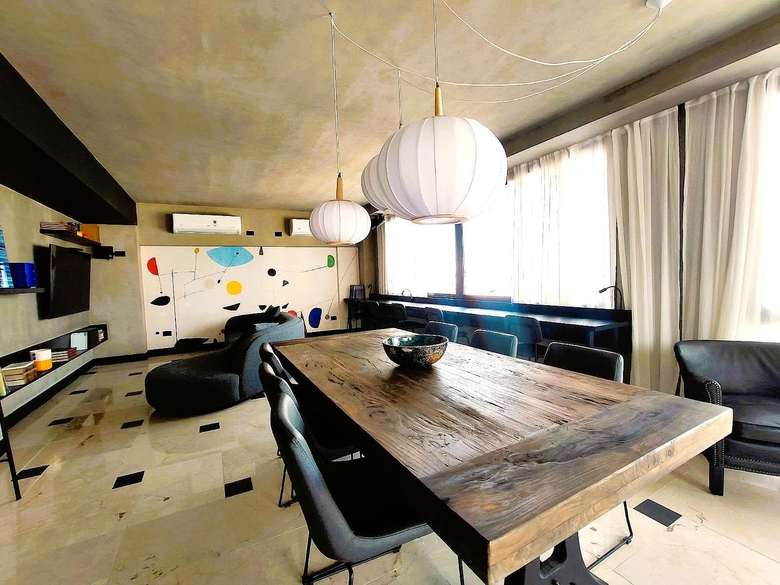 Salón de usos múltiples con mesa larga, sillas y ventanales.