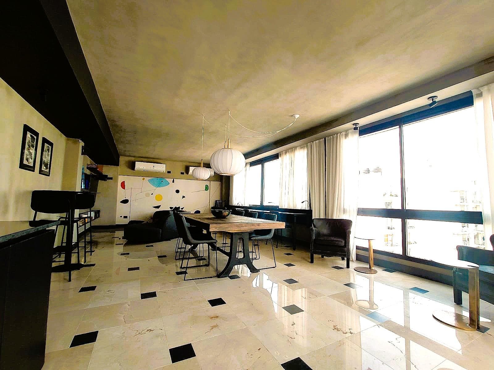 Amplio salón con mesa de comedor y sillones frente a ventanales.