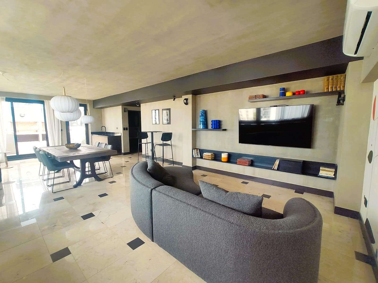Amplio salón con sillón, televisor y zona de comedor.