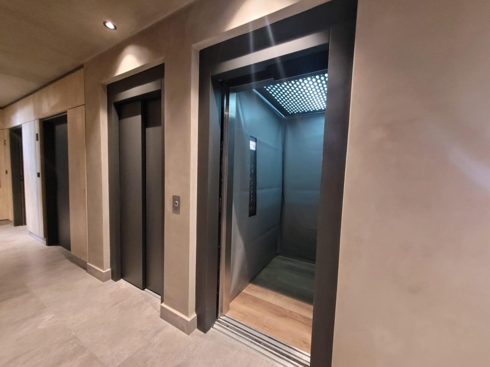 Dos ascensores, uno con puerta abierta mostrando el interior.