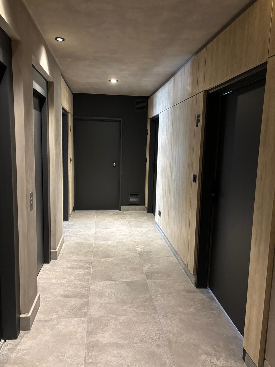 Pasillo de distribución con puertas de unidades y paneles de madera.