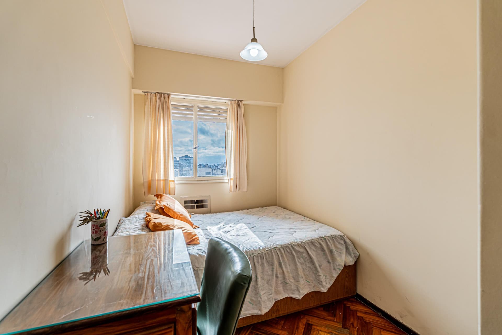 Dormitorio con cama, escritorio y ventana con vista al exterior.