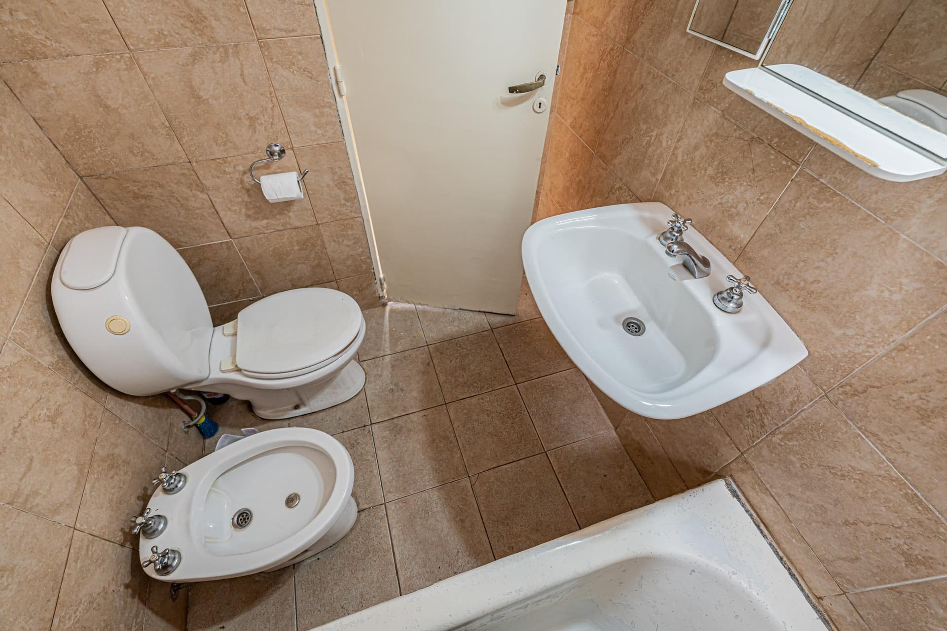 Baño completo con inodoro, bidet, lavatorio y bañera con azulejos.