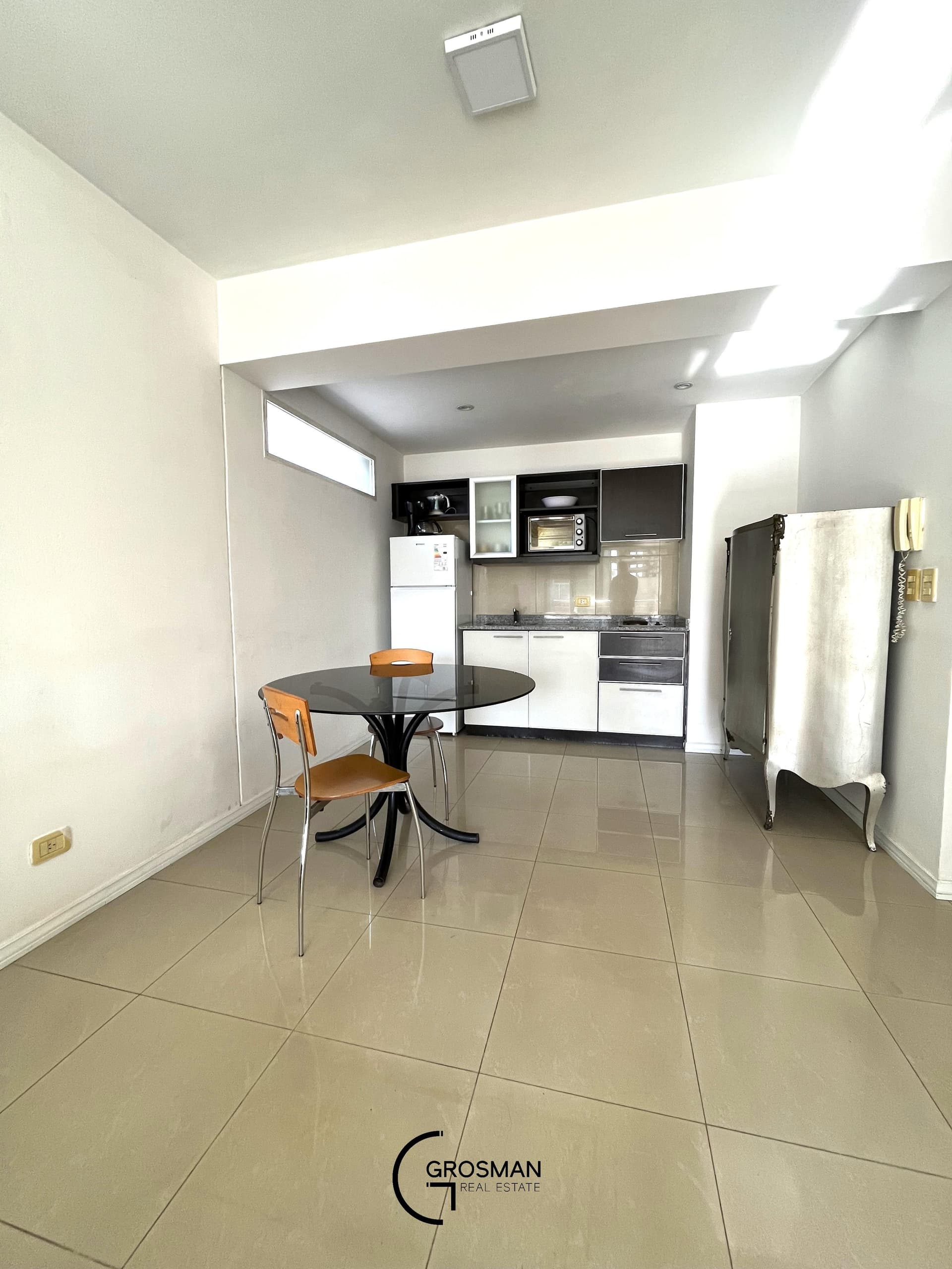 Cocina integrada con mesada, heladera y mesa de comedor.