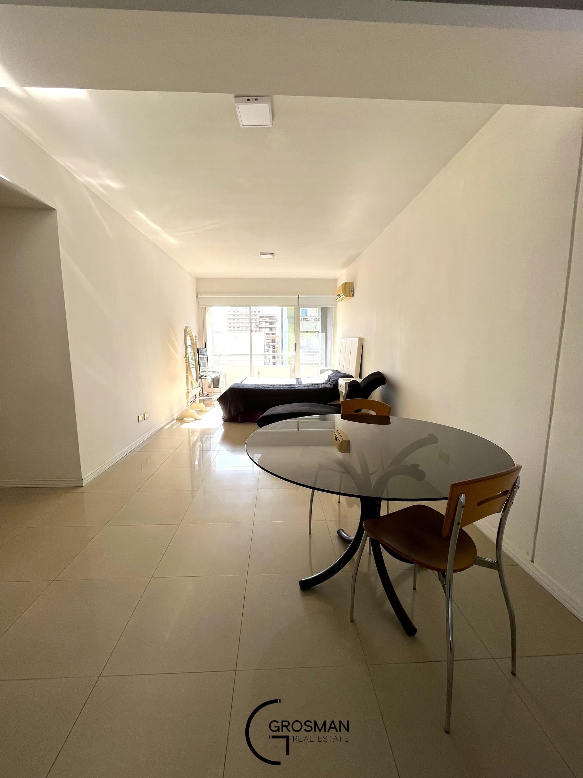 Ambiente principal con mesa de comedor y dormitorio al fondo.