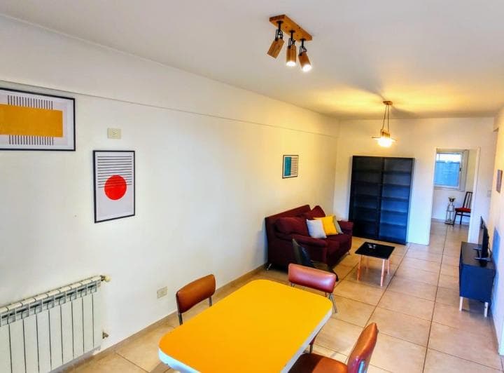 Amplio living con mesa de comedor, sofá y estantería en tonos claros.