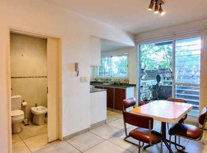 Baño con inodoro y bidet, con puerta abierta a la cocina y balcón.