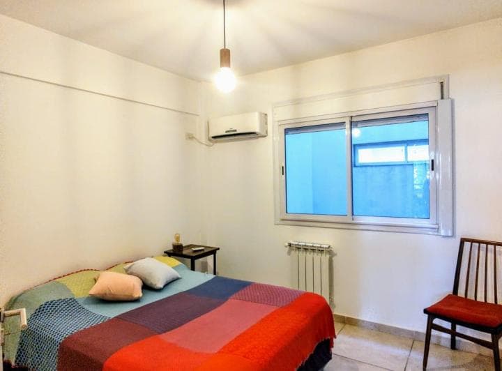 Dormitorio con cama doble, ventana con persianas y aire acondicionado.