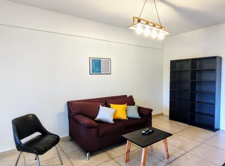 Living con sofá de dos cuerpos, mesa de centro y estantería negra.