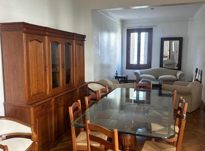 Living comedor con mesa, sillas, aparador de madera y sillones al fondo