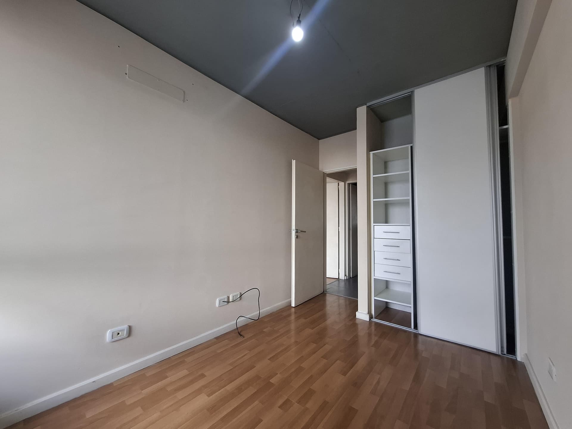 Dormitorio con placard, piso de madera, puerta al pasillo.