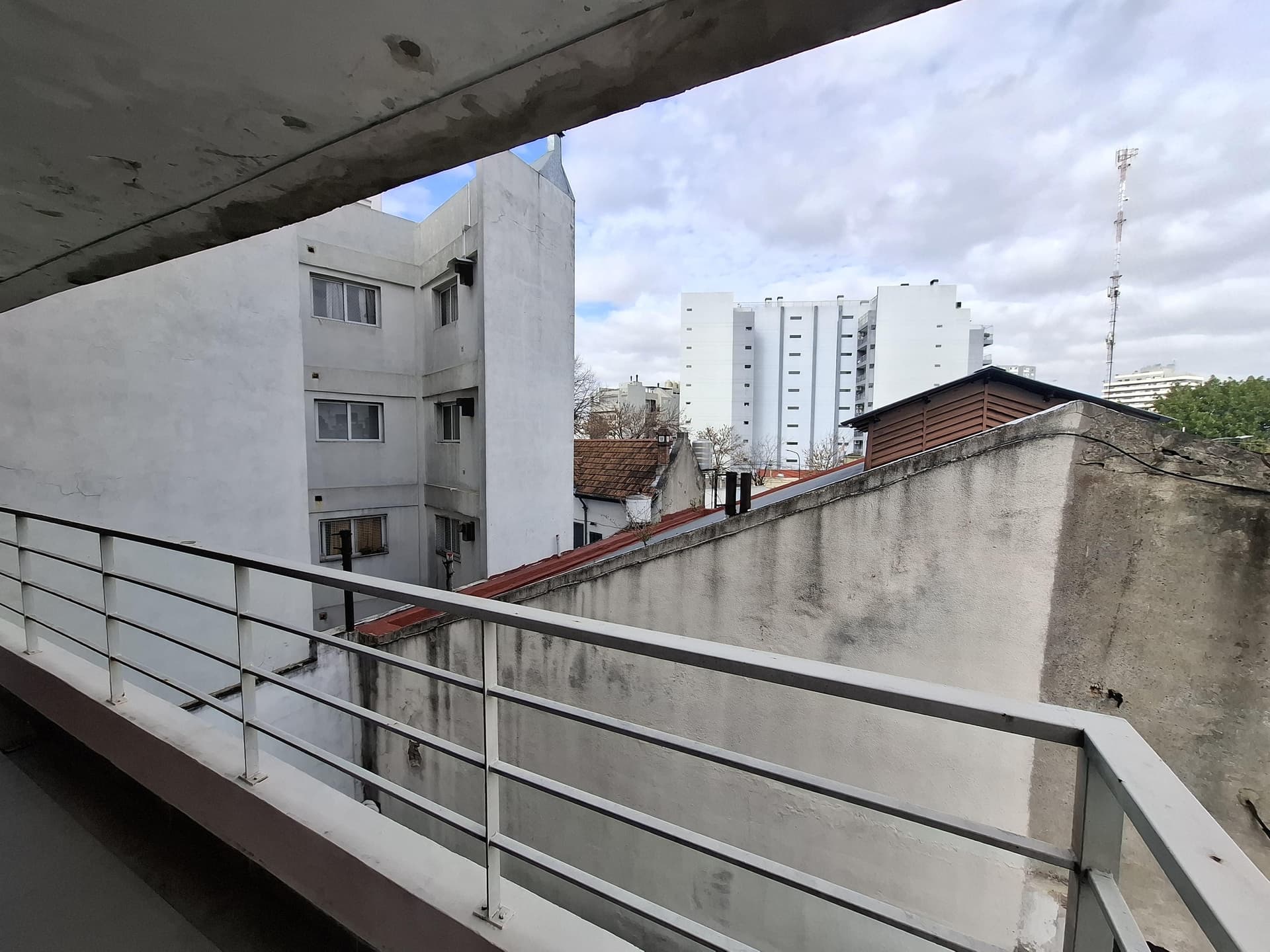 Vista urbana desde el balcón con edificios blancos y barandas.