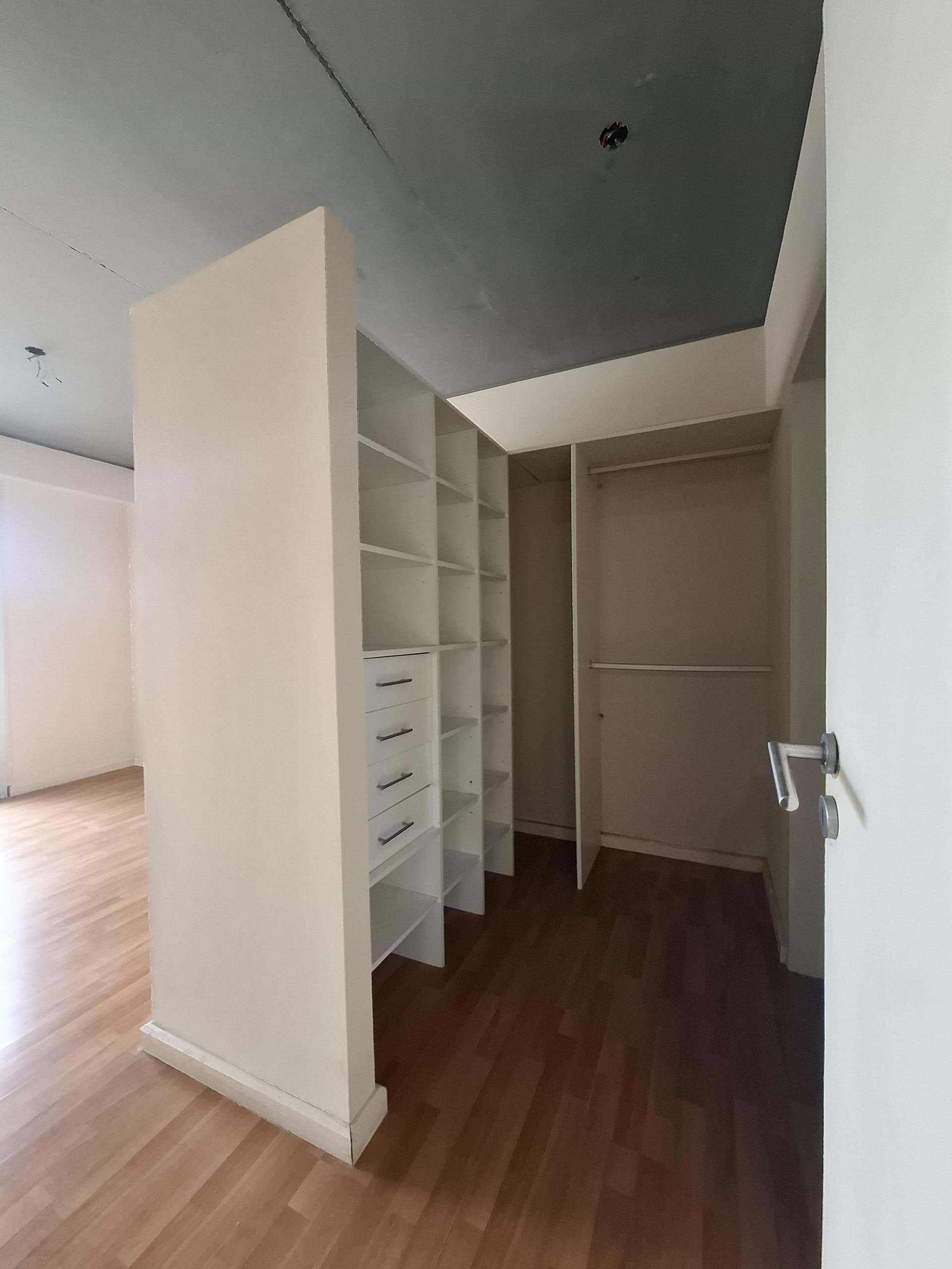 Vestidor abierto con estantes y cajones, piso de madera clara.