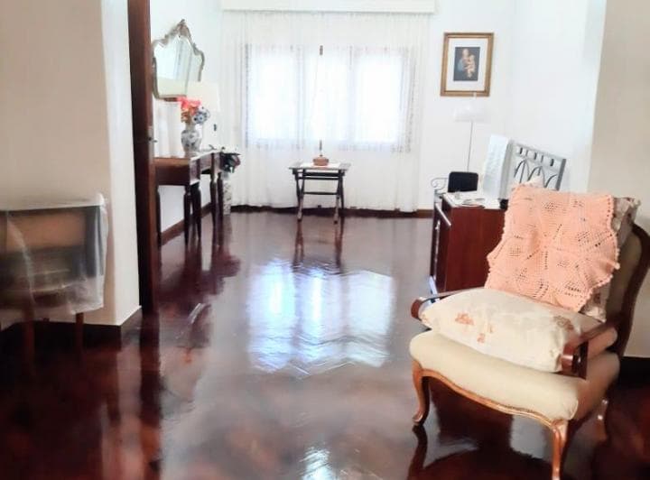 Living amplio con piso de madera, ventana, sillón tapizado y estufa.
