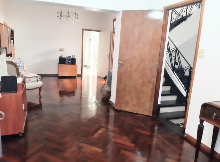 Pasillo con piso de madera, puertas, escalera de mármol y lámpara de techo.
