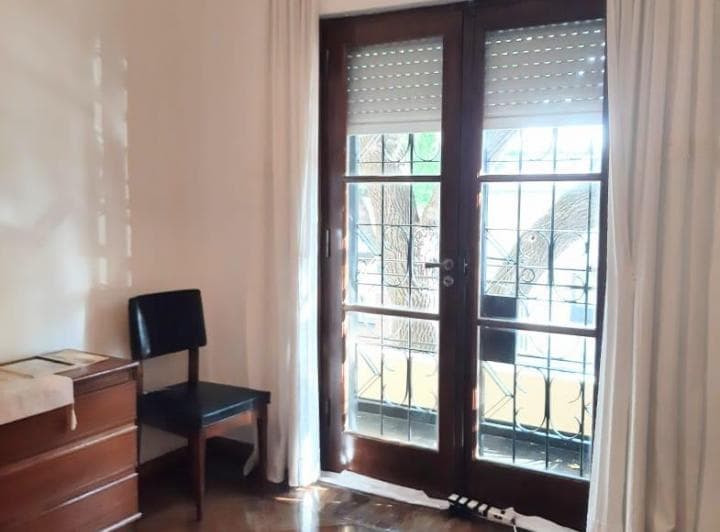 Dormitorio con puerta balcón de madera, persiana y vista al exterior.